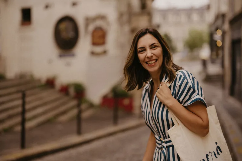 Mel Rolan sorrindo numa rua de paralelepípedos de Paris