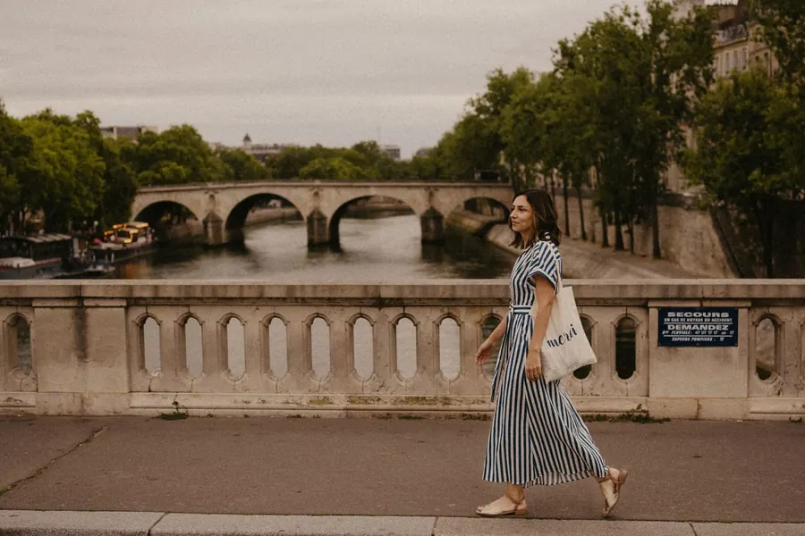 Mel Rolan caminhando sobre uma ponte do Sena, em Paris