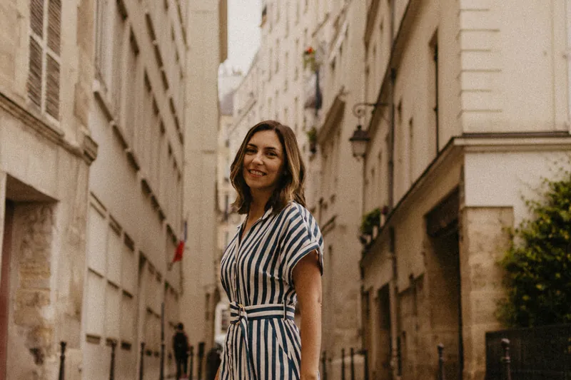 Mel Rolan com uma sacola de compras numa rua tranquila de Paris